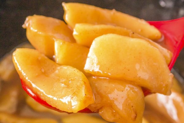 A red spoon full of caramelized apples.