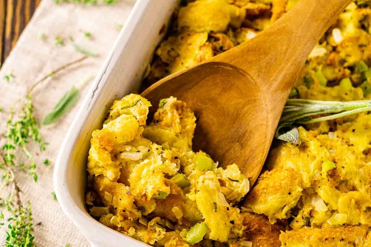 Thanksgiving stuffing recipe served in a white dish with a wooden spoon.