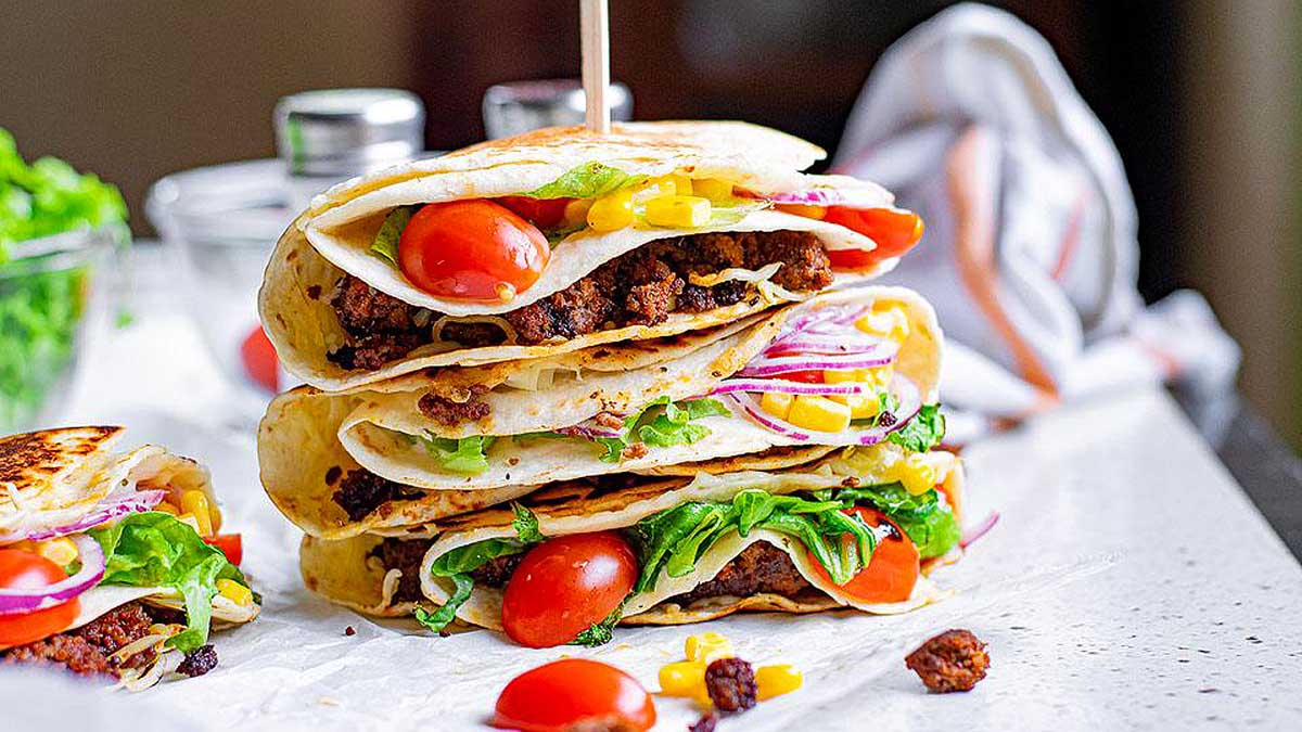 A stack of pitas with tomatoes and lettuce on top.