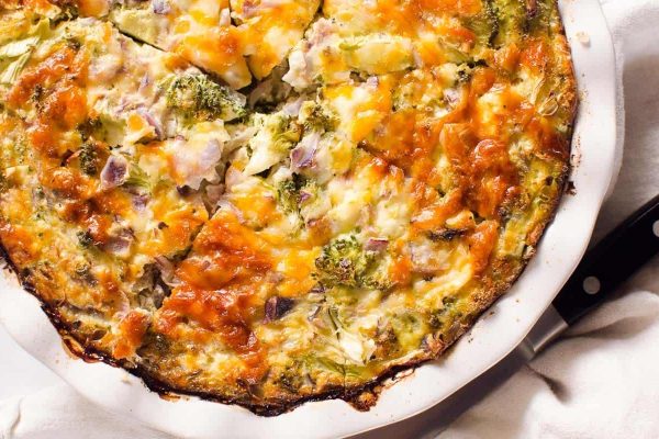 Delicious broccoli quiche recipe served in a white dish garnished with a knife.