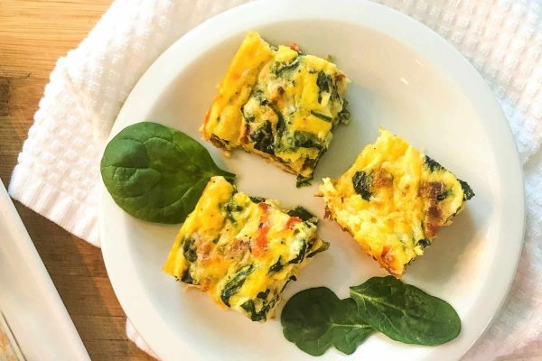 Four squares of spinach and egg quiche on a white plate, showcasing appetizing quiche recipes.