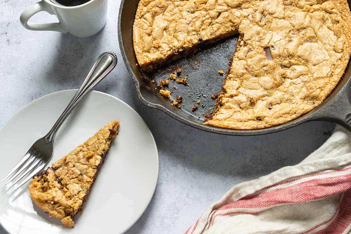 A skillet with a piece of cake and a cup of coffee.