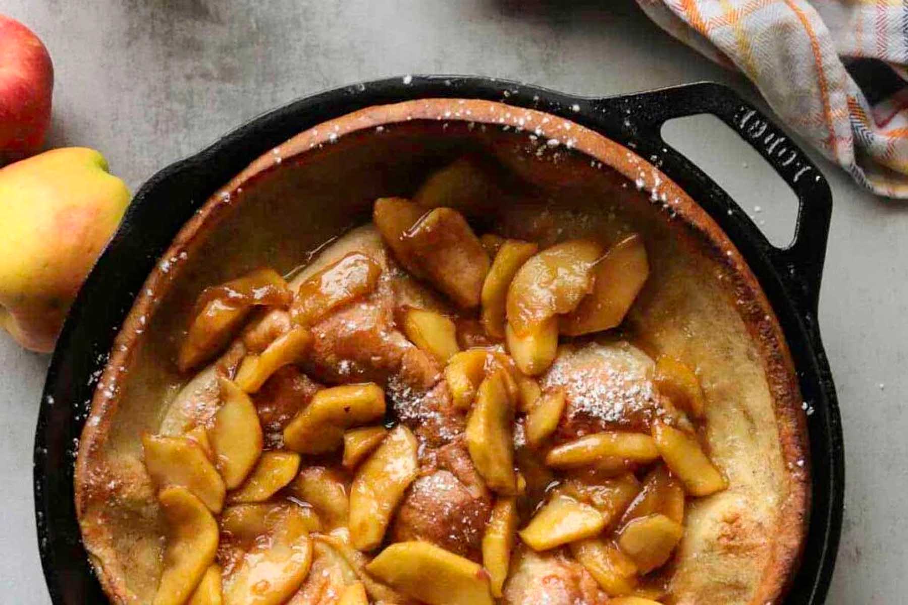 A cast iron skillet filled with apples and powdered sugar.