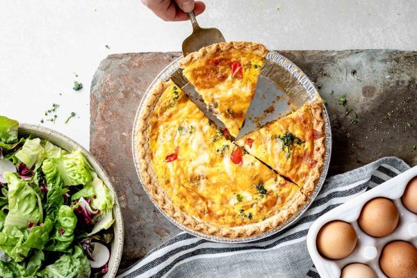 A person expertly cutting a mouthwatering quiche, showcasing their culinary expertise in creating unique and tantalizing recipes.