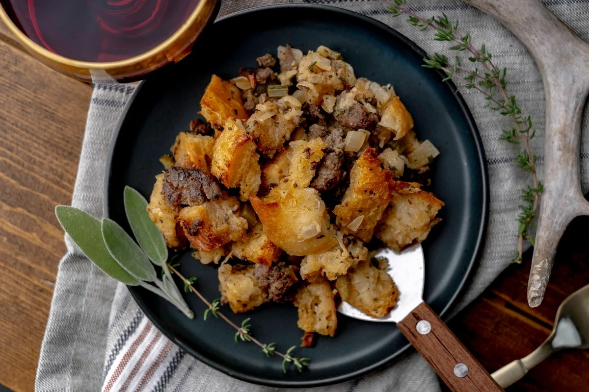 A plate of stuffing with a fork and sprigs of sage, perfect for holiday recipes.