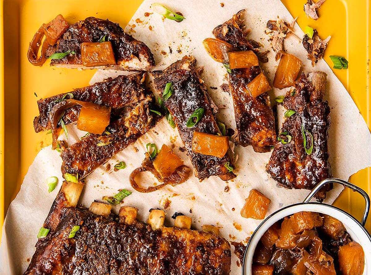 Hawaiian Inspired Ribs on a tray with sauce and onions, perfect for a luau.