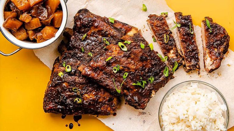 Bbq ribs on a plate with rice and sauce.