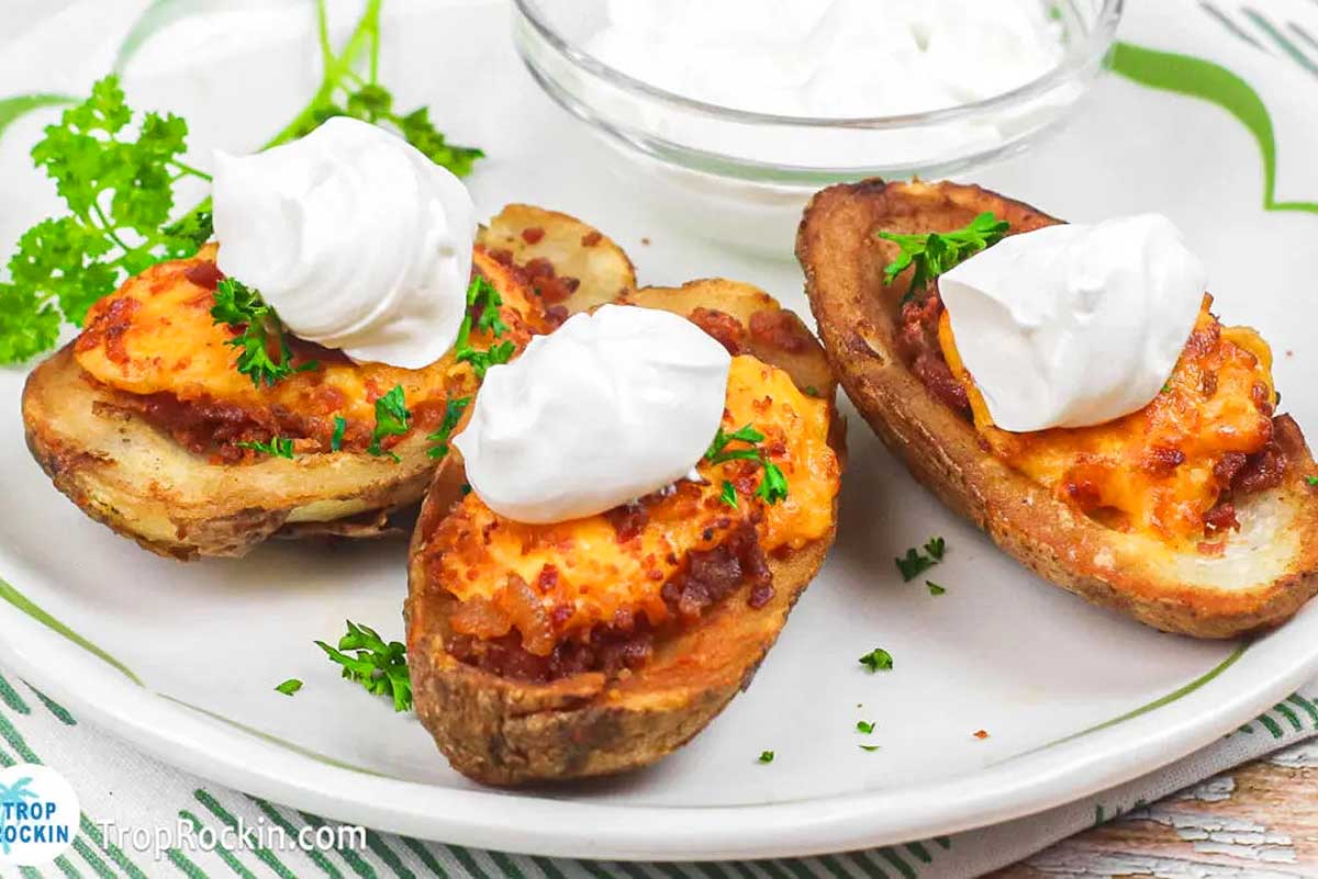 Three stuffed potatoes on a plate with sour cream and chives, perfect for pub food.