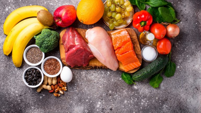 A variety of fruits, vegetables, and meats are arranged on a cutting board.