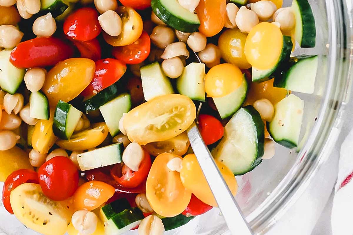A bowl filled with tomatoes, cucumbers, and chickpeas.