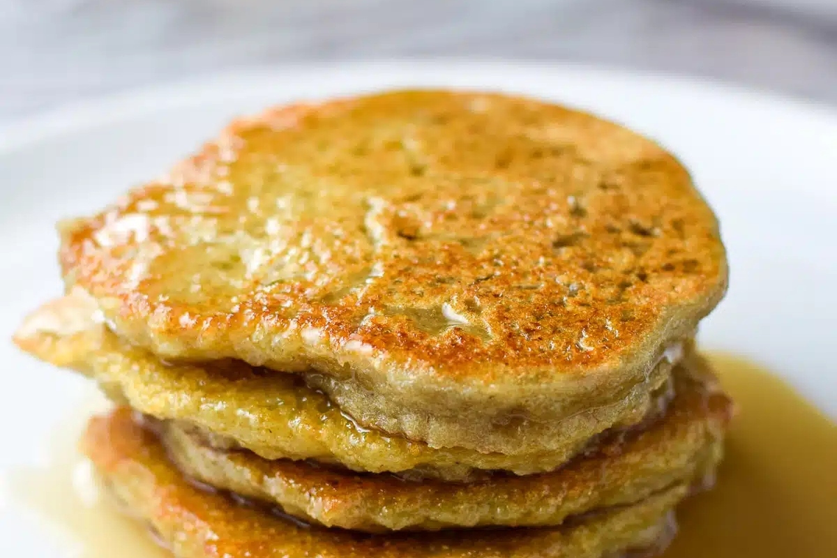A stack of German pancakes with syrup on a white plate.