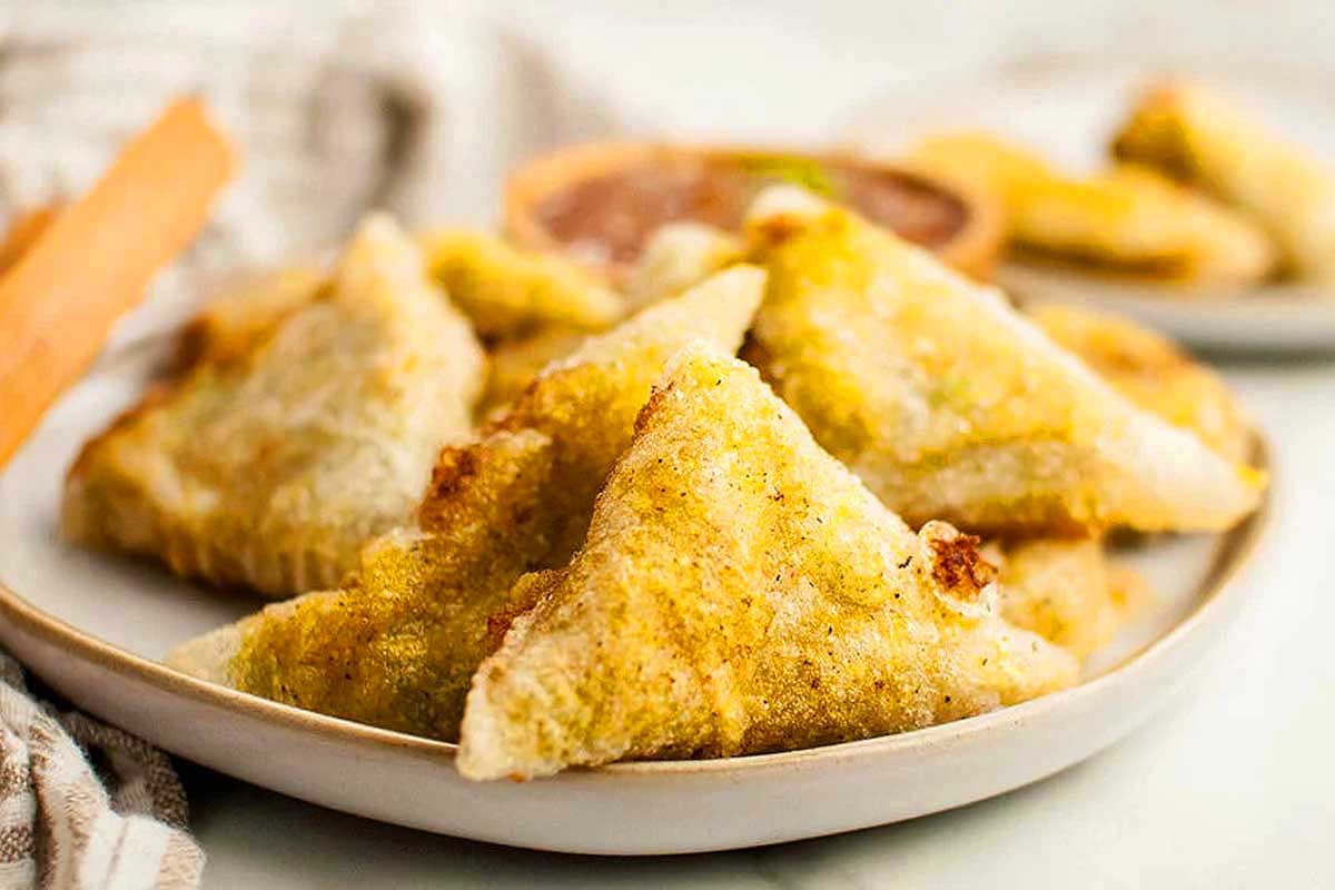 Fried samosas on a white plate.