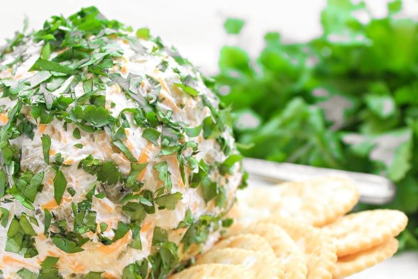 A savory cheese ball recipe served with crispy crackers and garnished with fresh parsley on a plate.