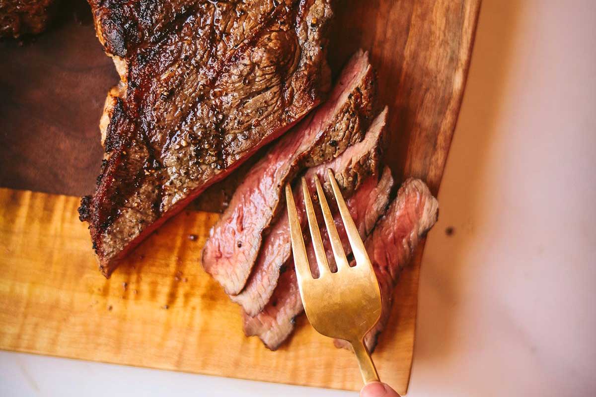 A romantic night date featuring a succulent piece of steak on a cutting board, elegantly paired with a fork.