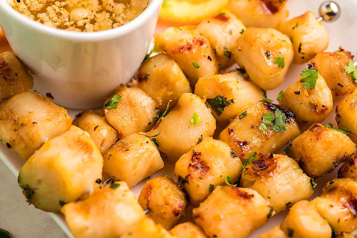 Scallops threaded onto skewers and served with a dipping sauce.