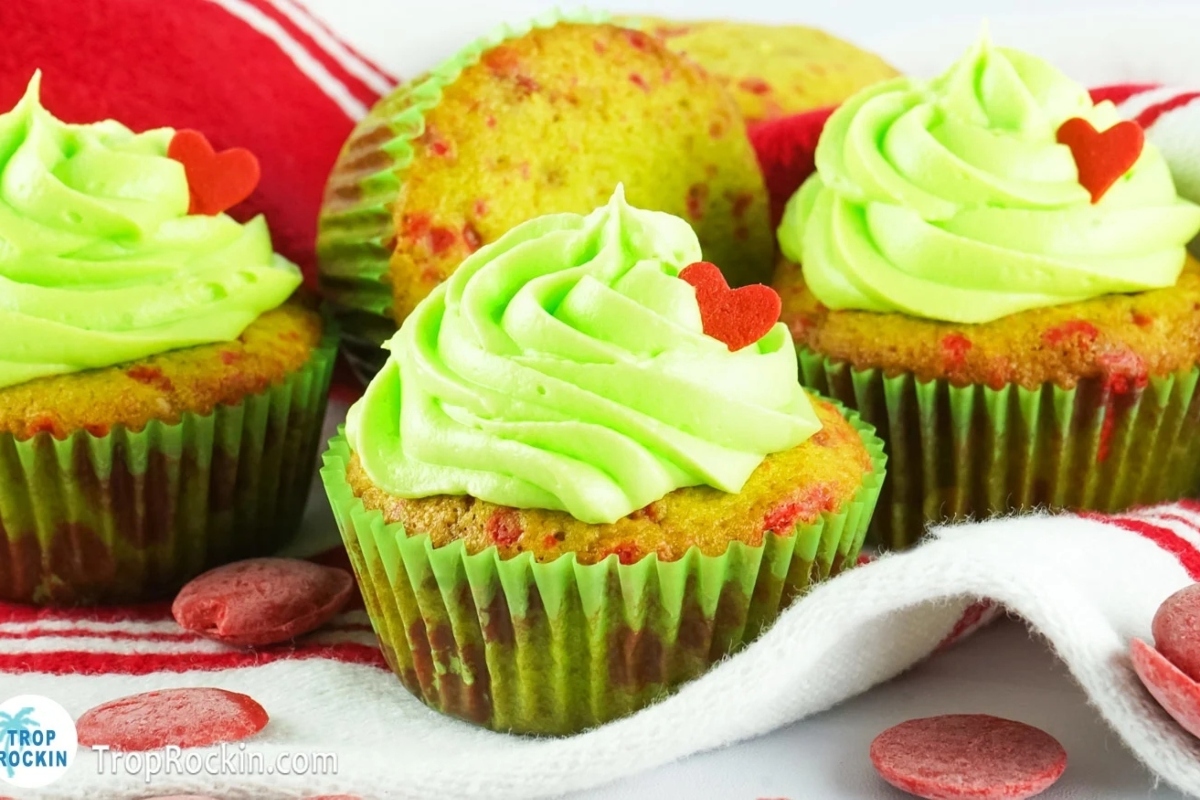 Grinch-themed cupcakes with green frosting and red hearts.
