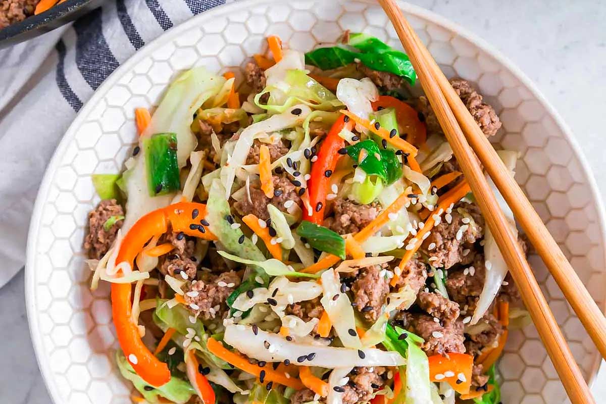 A bowl of beef and vegetable stir fry with chopsticks.