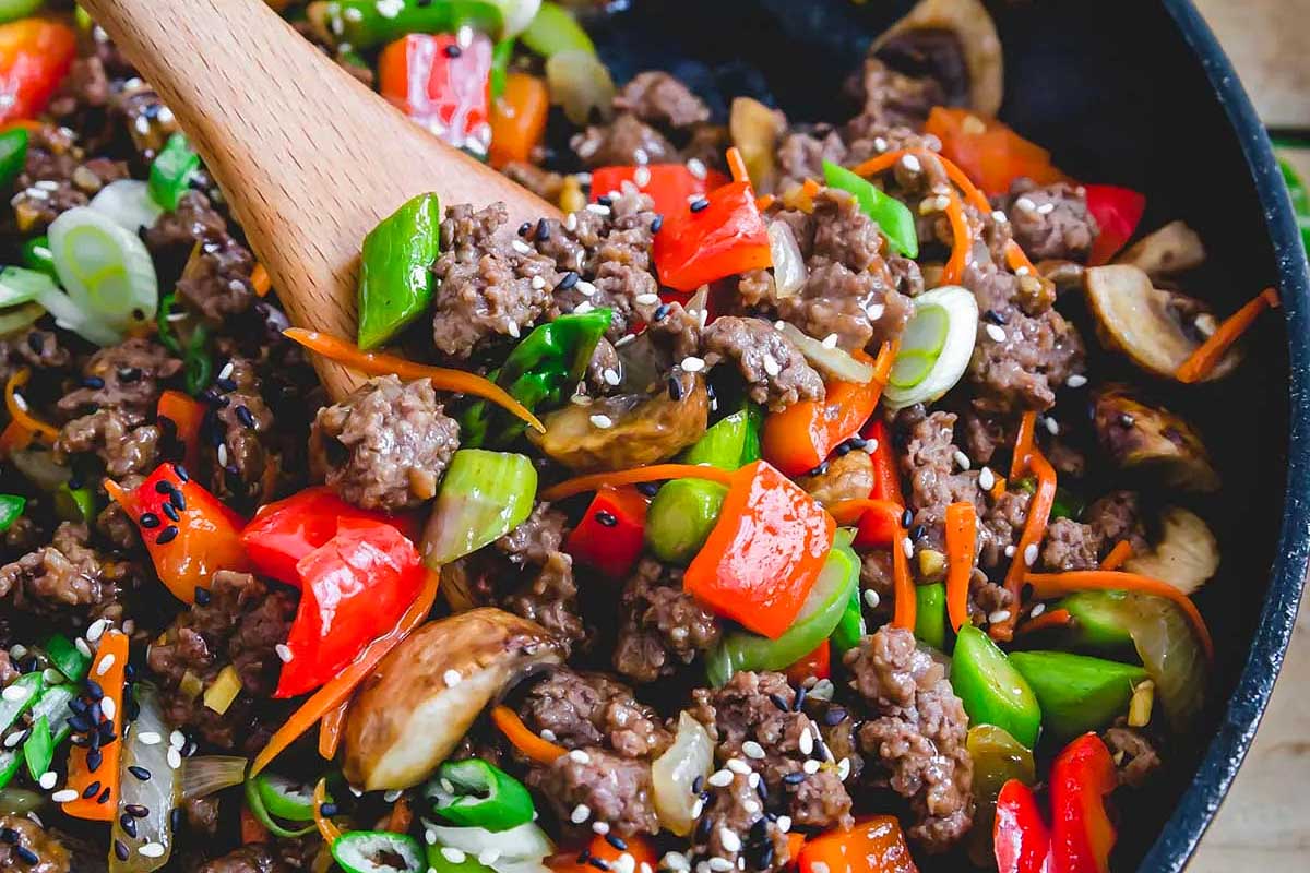 A skillet full of vegetables and meat stir fried in sesame oil.