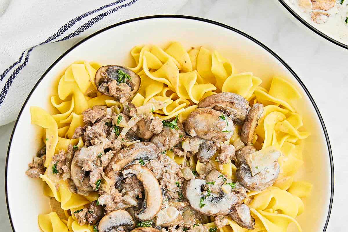 A bowl of pasta with mushrooms and sauce.