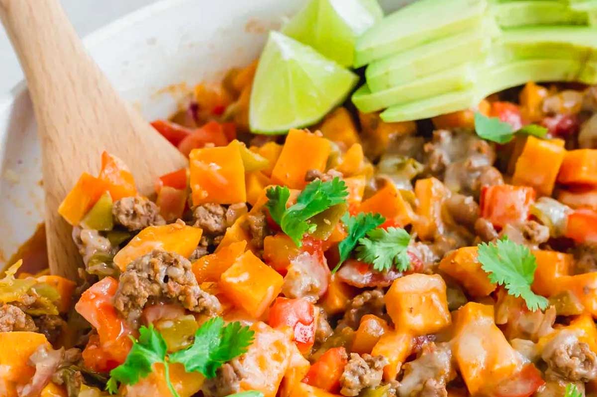 Mexican sweet potato casserole in a white bowl with a wooden spoon.