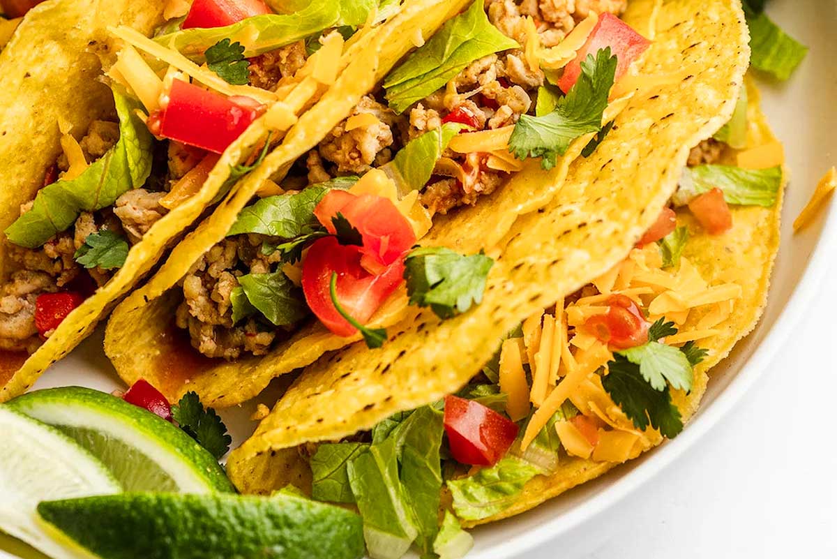 Meat tacos on a white plate.