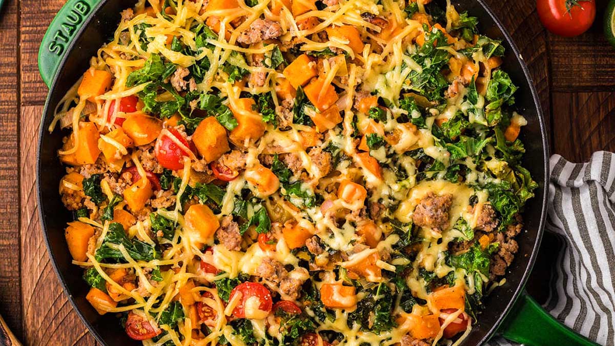 A skillet full of vegetables, meat and cheese.