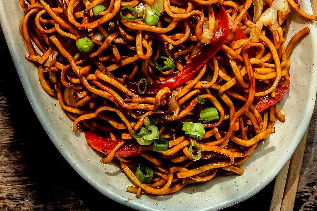 Chinese noodles in a white bowl with chopsticks.