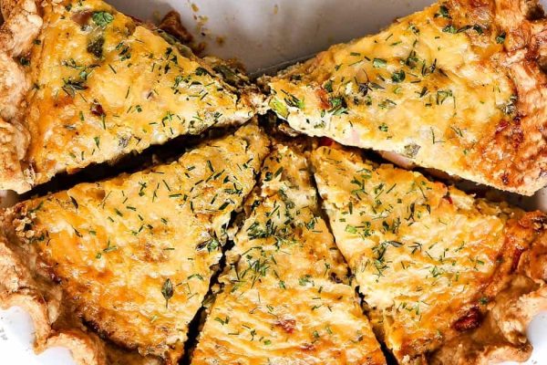 A mouthwatering quiche recipe with a slice cut out of it.
