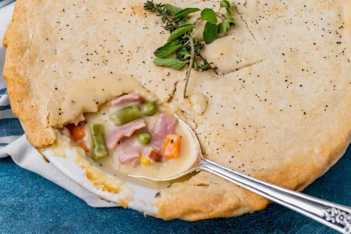 A spoon is used to scoop out a delicious ham pot pie.