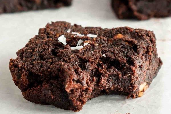A close up of a decadent chocolate brownie on a piece of paper, tempting the taste buds with its rich aroma.