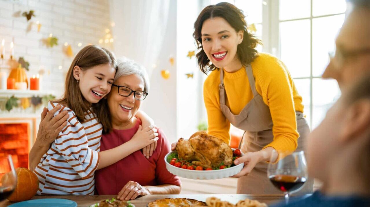 A woman is serving a turkey to a family at a dinner table.