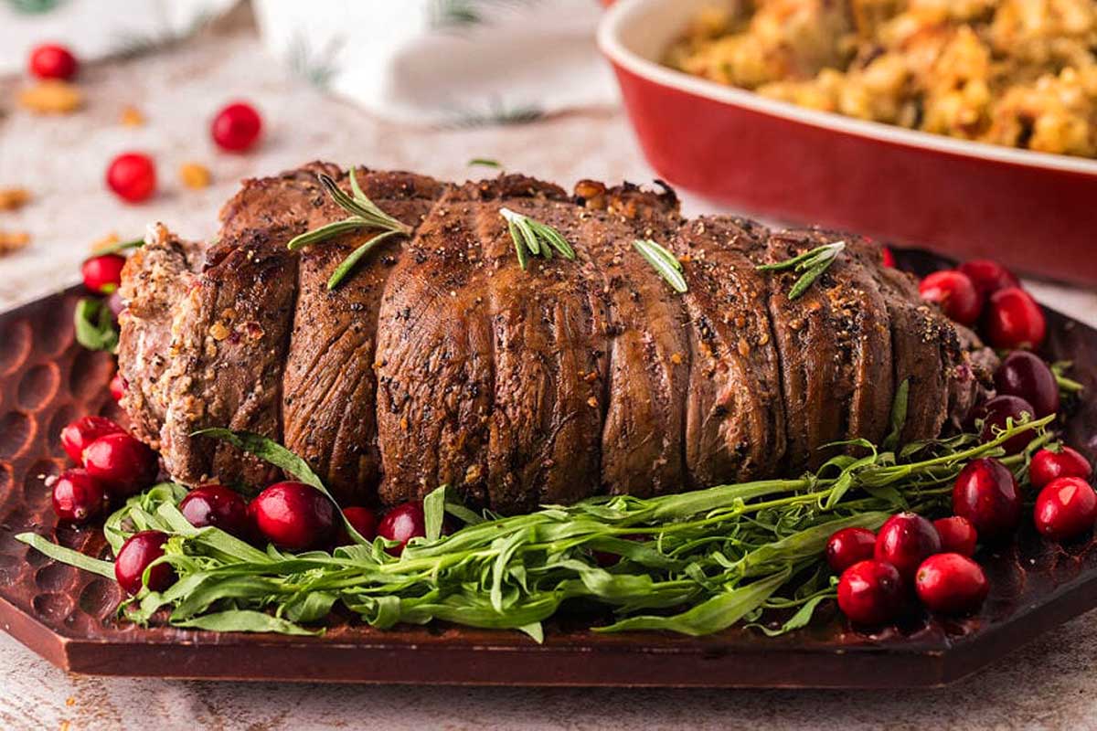 A festive friends giving roast with cranberries and greens on a plate.