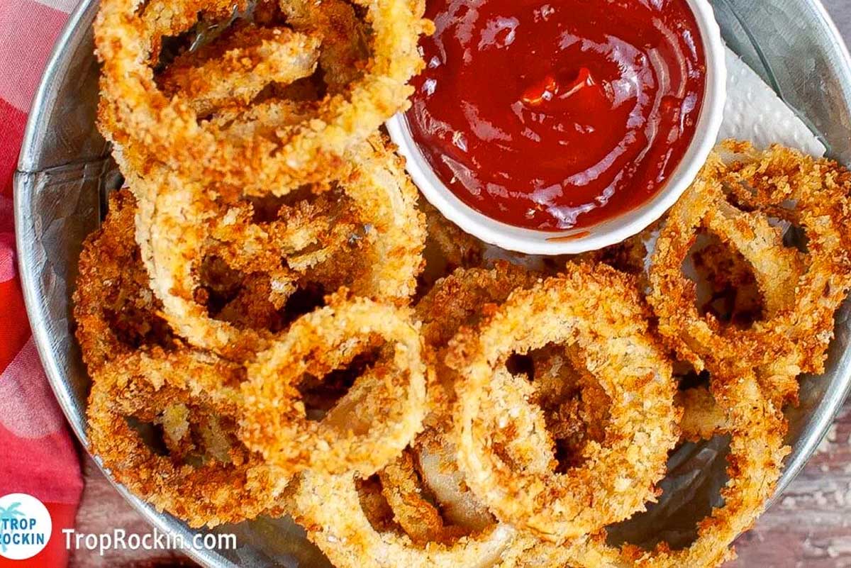 Classic pub food - crispy fried onion rings served on a plate with a side of tangy ketchup.
