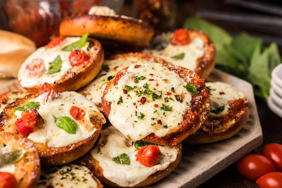 Appetizers: Pizza bagel bites on a plate with tomatoes and basil, perfect for New Year's Eve.