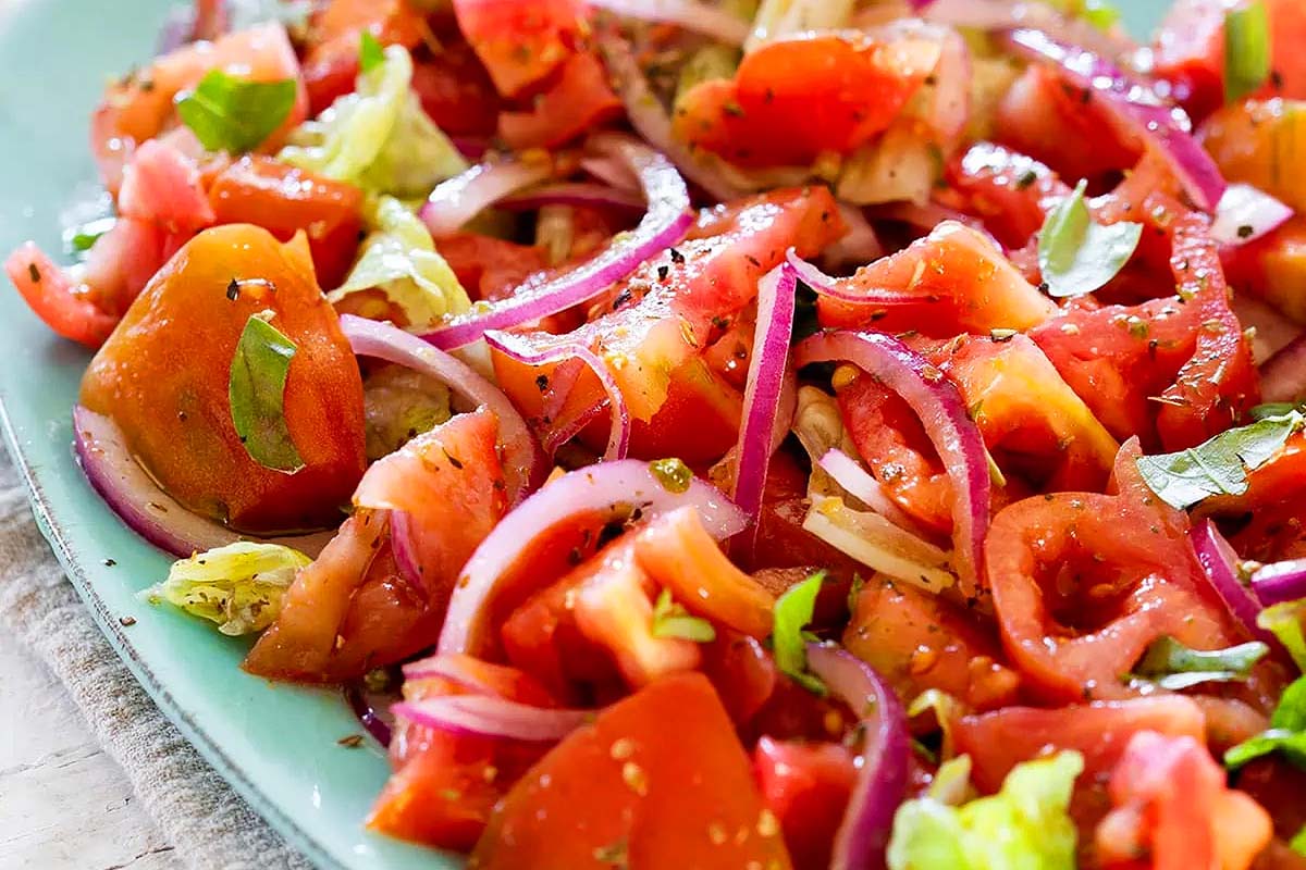 An Italian salad with tomatoes, onions, and lettuce on a plate.