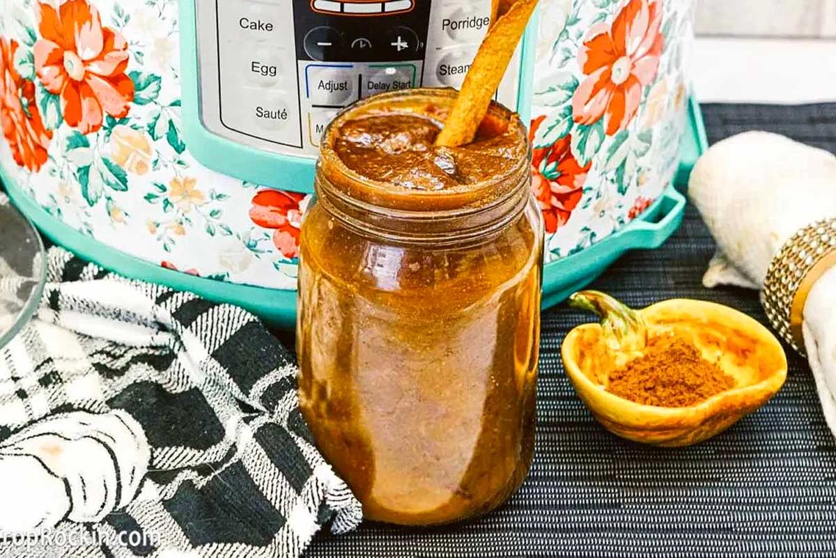 A jar of sauce in front of an Instant Pot.