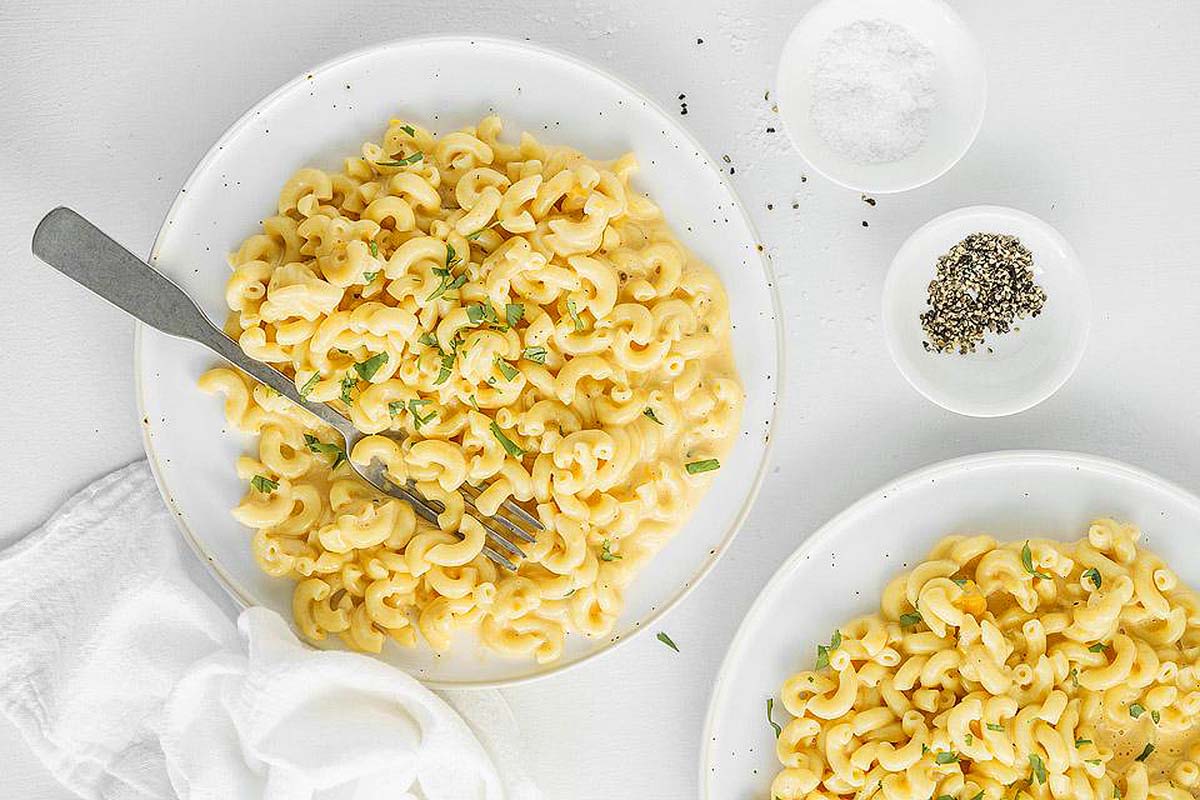 Two plates of macaroni and cheese on a white background.