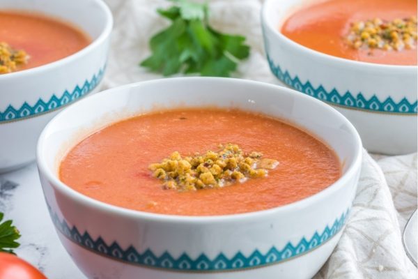 Three bowls of creamy tomato soup with parsley.