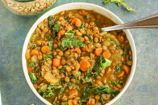 A bowl of lentil and kale soup with a spoon.