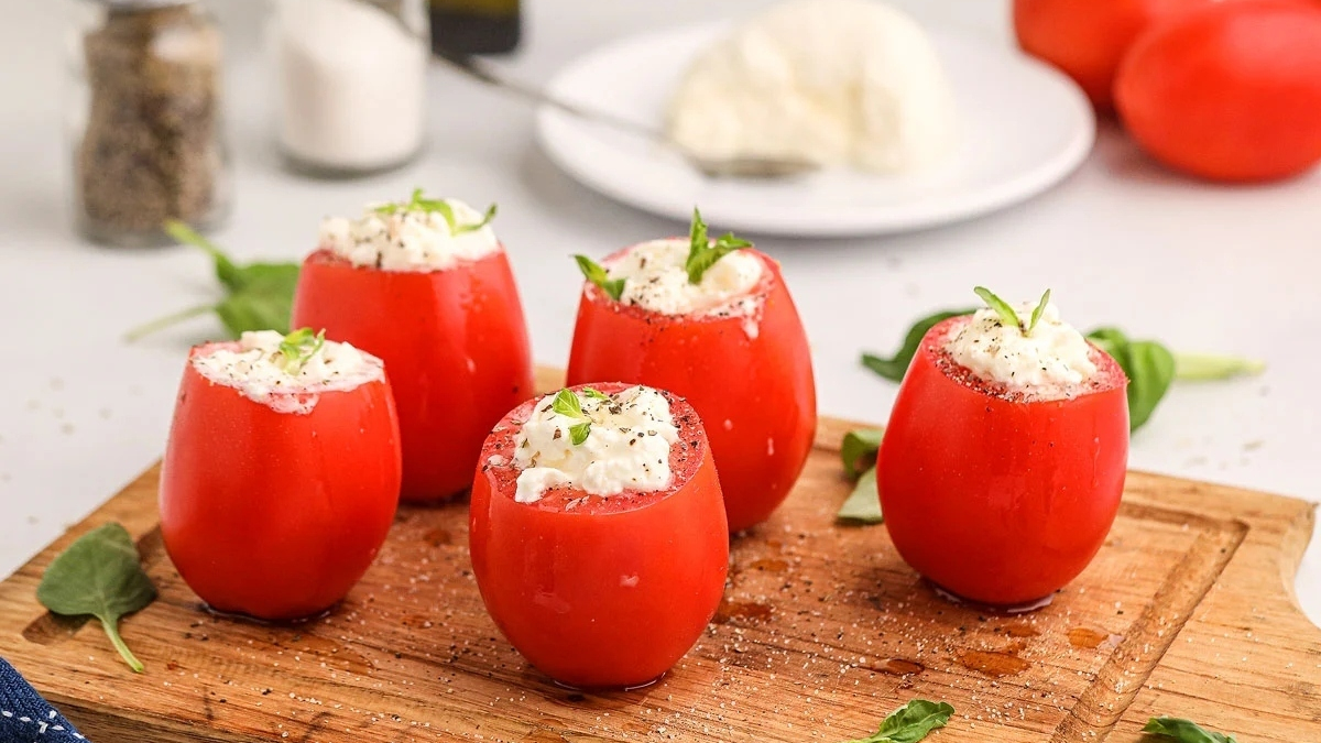 Appetizer: Tomatoes stuffed with feta cheese on a wooden cutting board for New Year's Eve celebration.
