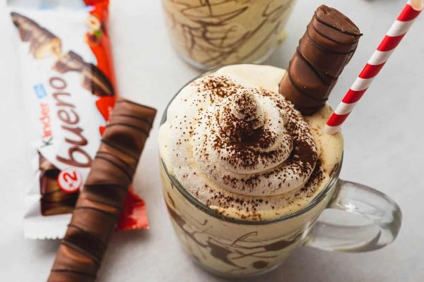 A cup of coffee with whipped cream and a chocolate bar, perfect for indulging in milkshake recipes.