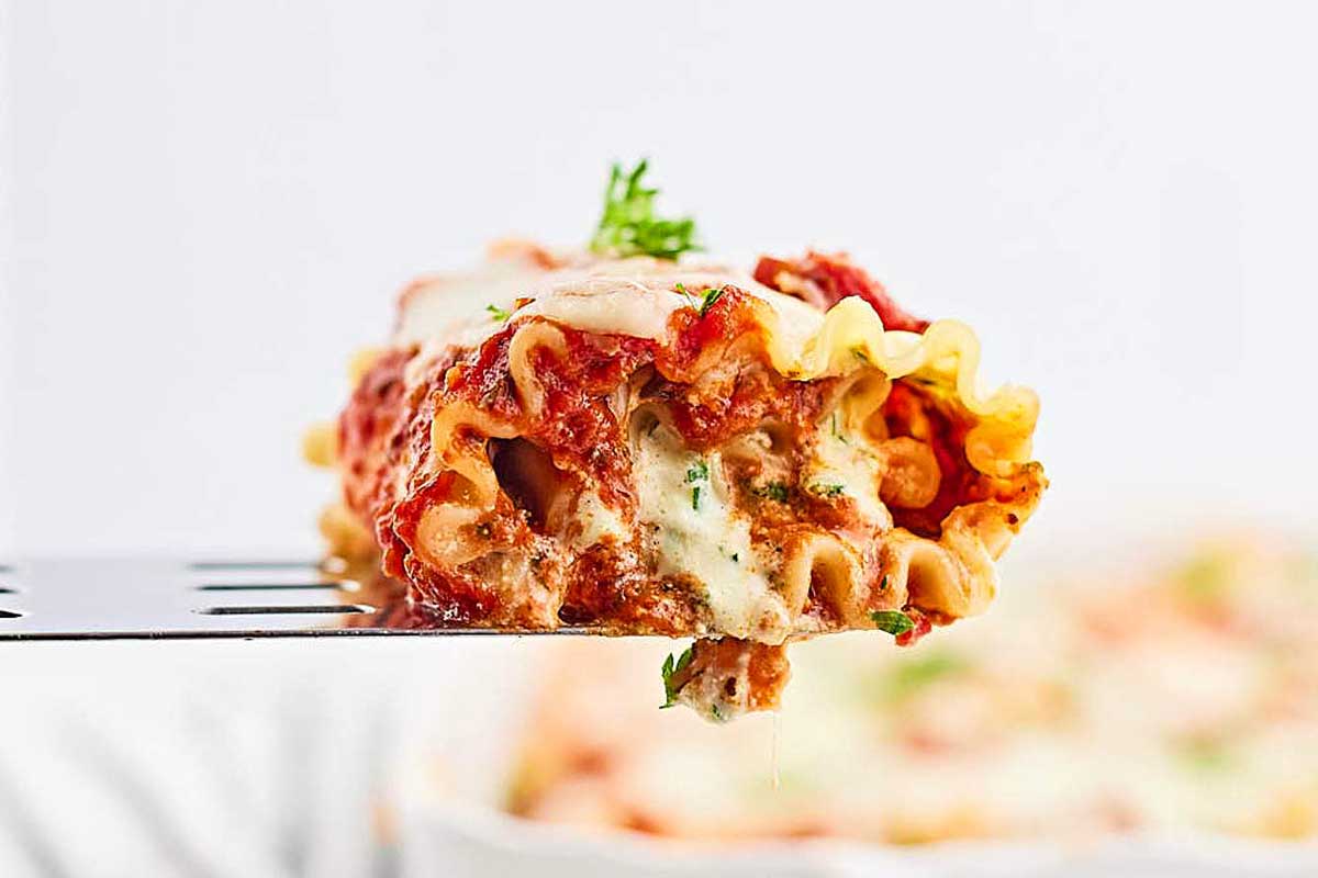 A fork is being used to pick up a piece of lasagna.