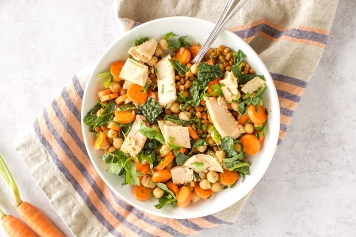 A bowl of chicken and lentil salad with carrots and carrots.