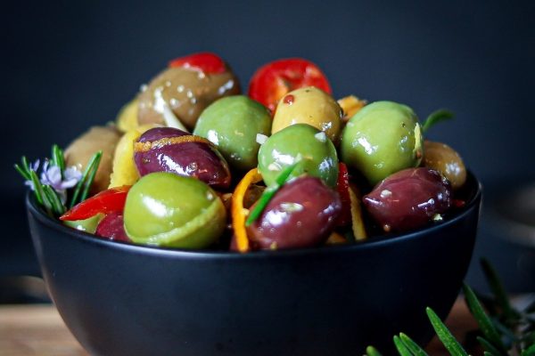 Olives and peppers in a black bowl.