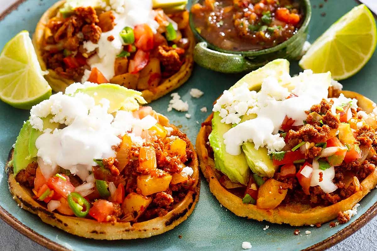 Mexican tacos with guacamole and sour cream on a plate.