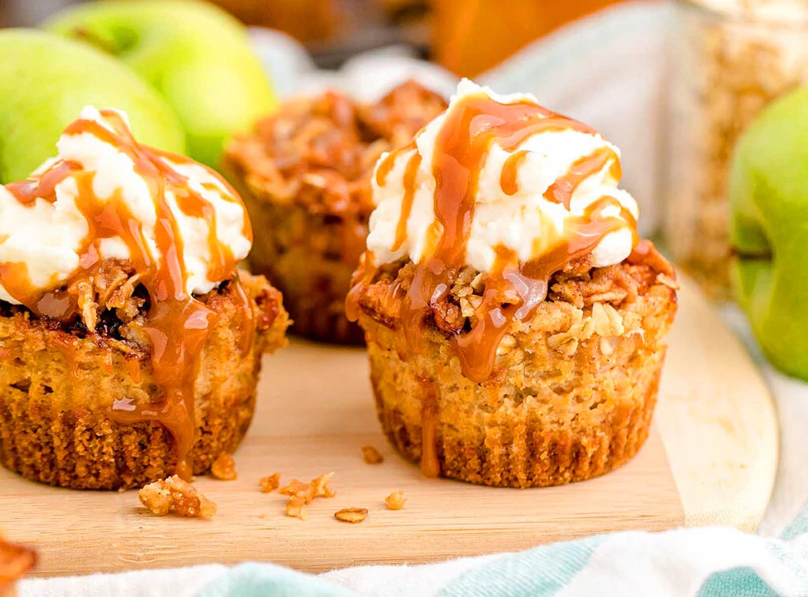 Caramel apple muffins on a wooden cutting board.