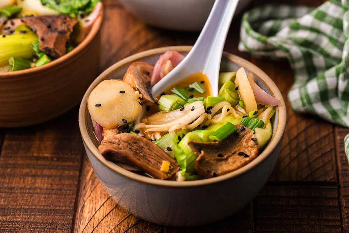A bowl of soup with mushrooms and vegetables in it.