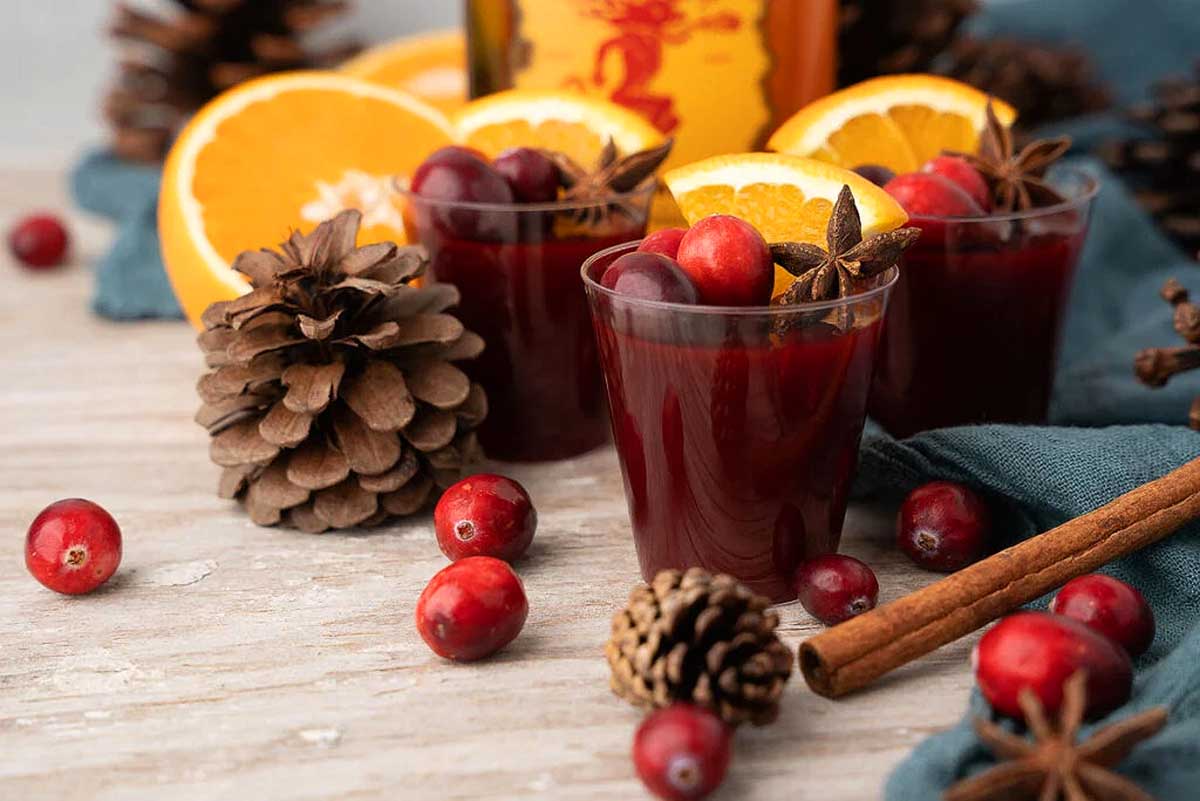 Fall cocktail with cranberry mulled wine, oranges, and pine cones.