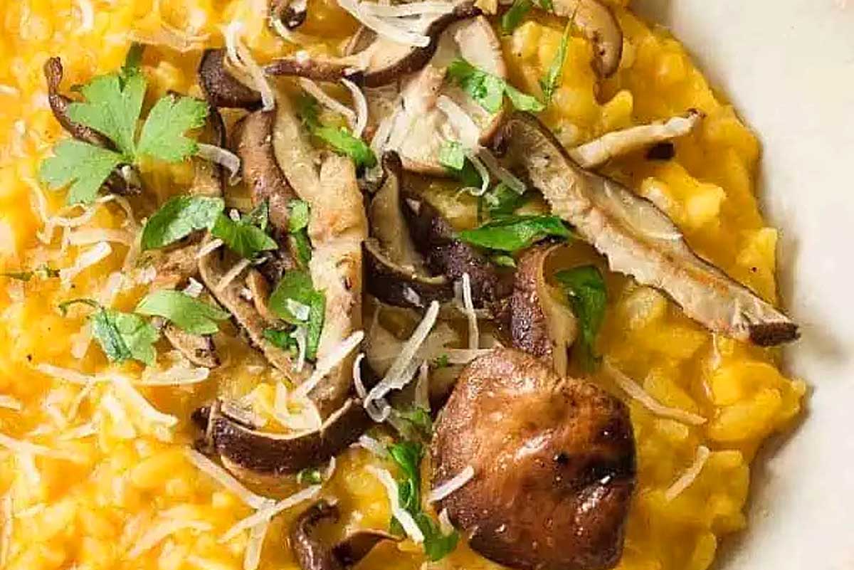 A delicious bowl of risotto, generously giving off the rich aroma of mushrooms and garnished with fresh parsley.