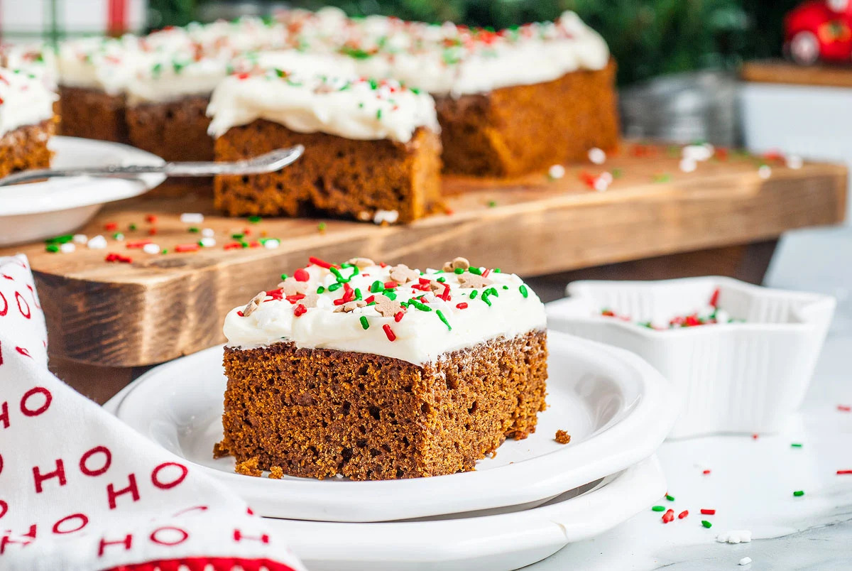 A slice of gingerbread cake on a plate with Christmas icing.
